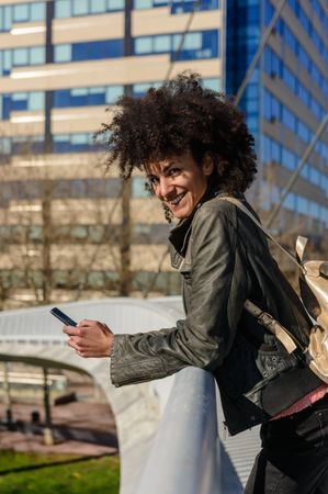 Woman with afro hair looking at her phone while walking.