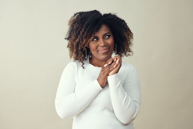Curious Black woman clasping her hands together while looking off in thought
