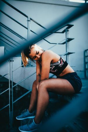 Young woman in sports bra sitting on stadium stairs