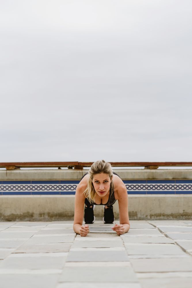 Sportswoman practicing plank on lonely sandy seashore
