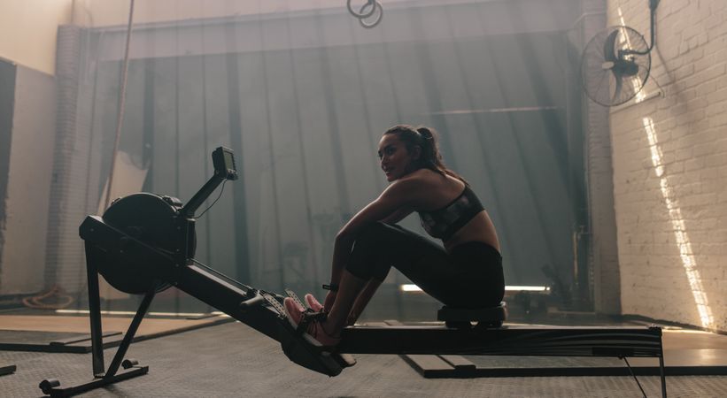 Woman sitting rowing machine at gym