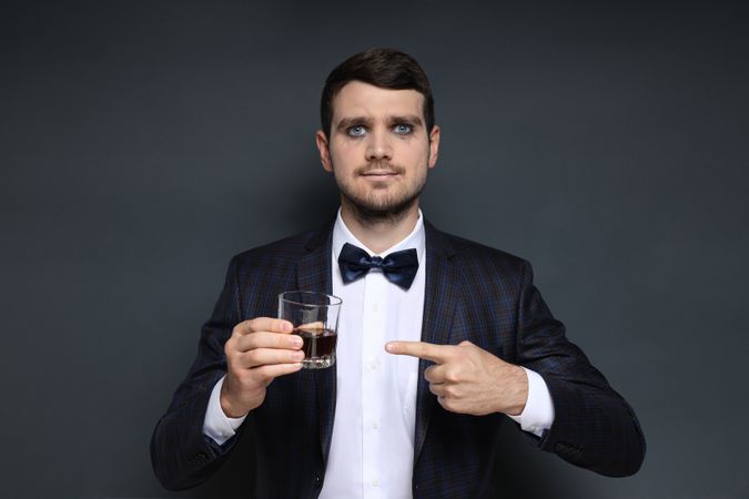 A man in a zombie costume with a drink in his hand on a dark background
