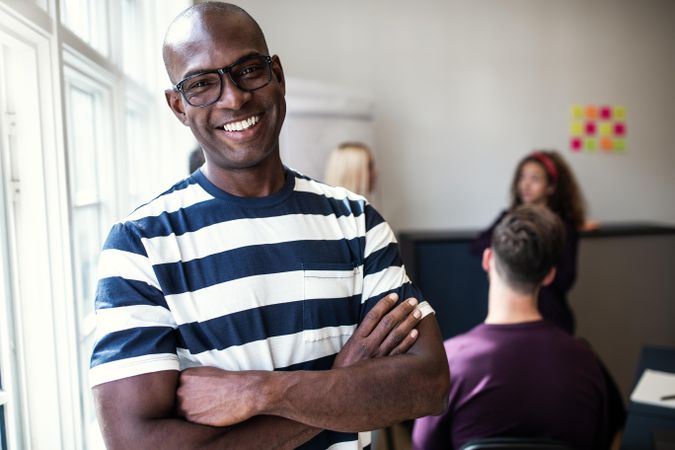 Black man smiling in office with arms folded