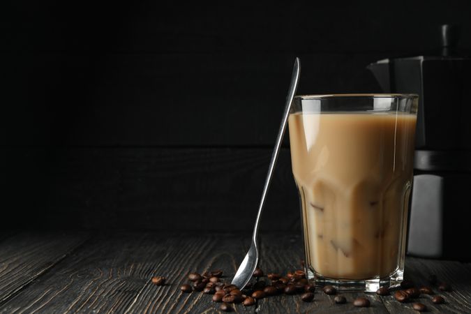 Composition with ice coffee and coffee seeds on wooden background