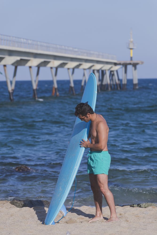 Male surfer standing with his board near the coast