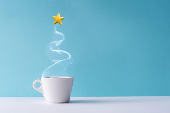 Christmas tree made of steaming coffee or hot drink with yellow star cookie