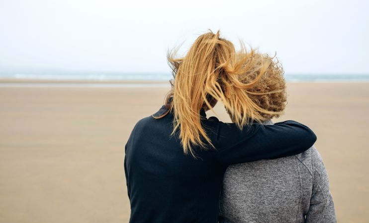Back view of older and younger woman looking at sea