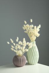 Textured round vase and tall vase filled on table with dried grass in grey room, vertical