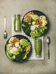 Two vegetarian bowls,  with smoothie, on placemat, vertical composition