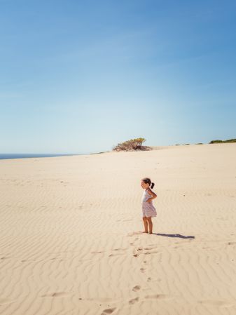 Cute little girl standing at sand dune