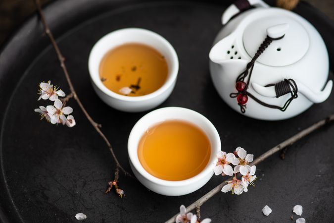 Cups of tea and pot with floral petals
