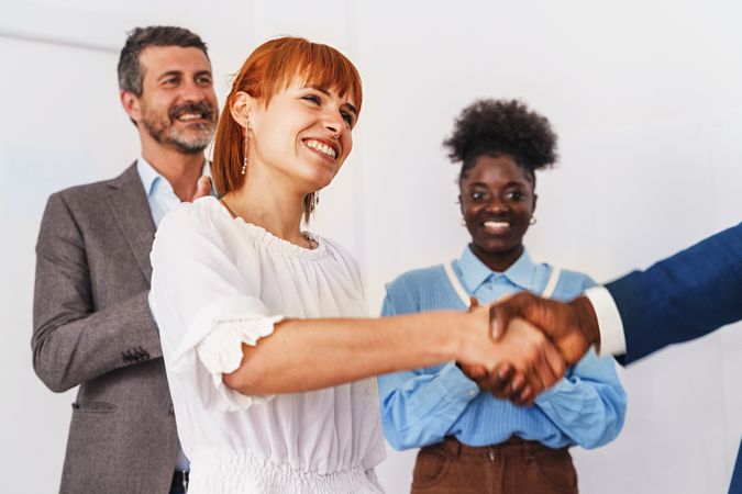 A white woman shaking hands with a Black man in a professional office