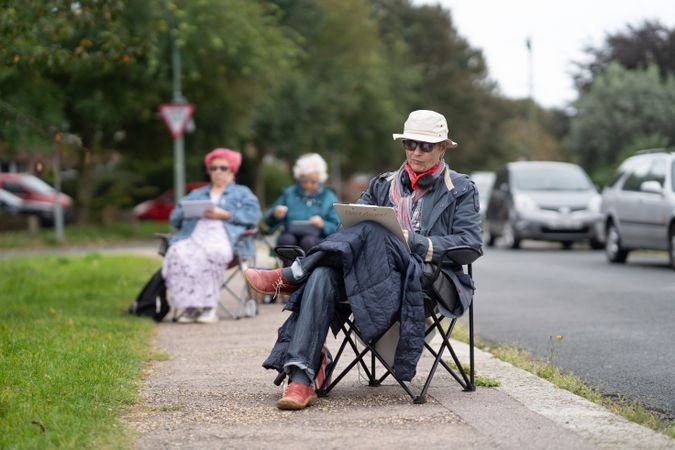 Older people sitting on sidewalk during drawing class
