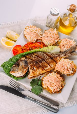 Top view of fried fish, salad and fried plantain
