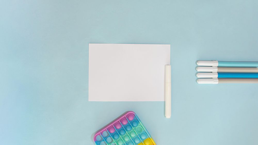 Flat lay of pens and paper on blue background