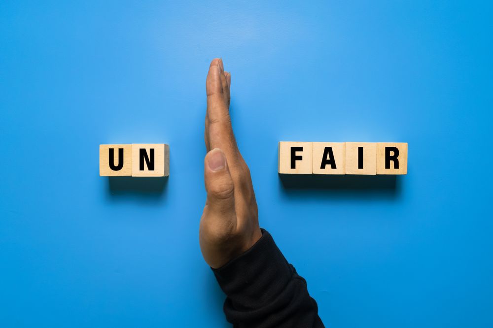 male hand put away first two letter from unfair word to be read fair isolated on blue background. fairness concept