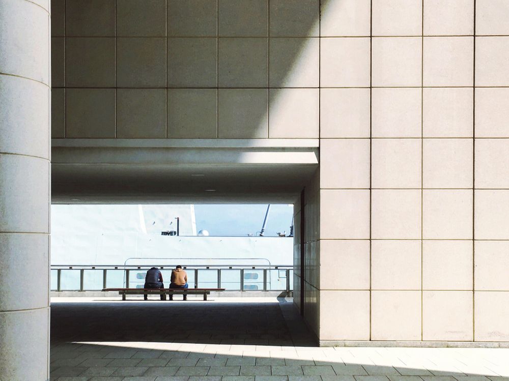 Two men sitting on bench outdoor near balustrade