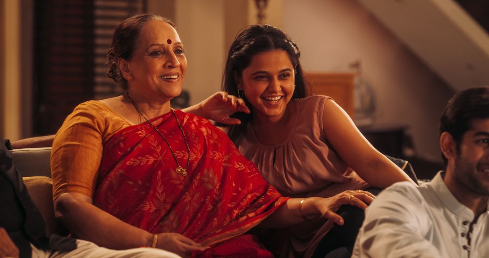 Portrait of Happy Indian Mother and Daughter Enjoying Movie Playing on TV at Home Together with Their Family.