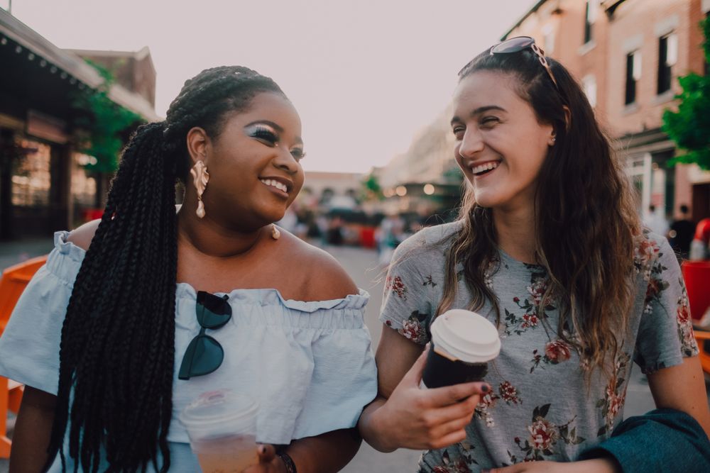 Happy multiethnic laughing modern women with coffee cups