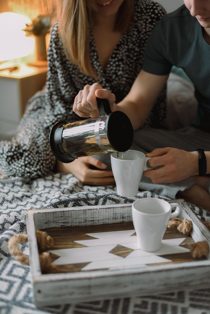 Man and a woman drinking tea in their bedroom