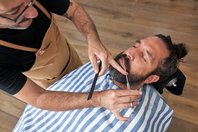 Professional barber cutting hair of customer in salon