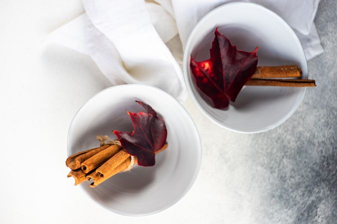 Top view of winter table setting of cinnamon sticks in bowls with autumn leaves