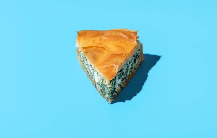 Spinach pie slice minimalist on a blue background