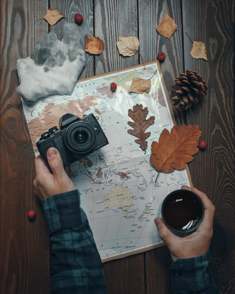 Person holding  mug and camera above map