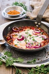 Fragrant shakshuka with onion rings in pan
