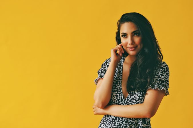 Smiling Hispanic woman wearing dress standing in yellow room