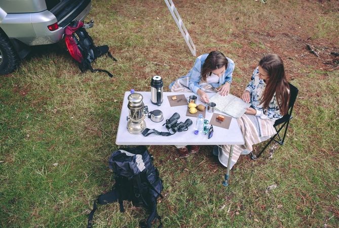 Young women consulting road map in campsite
