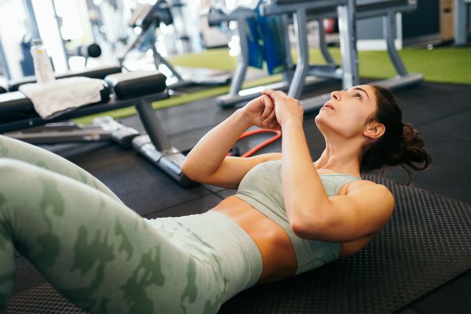 Athletic female, wearing sportswear, on yoga mat doing situps