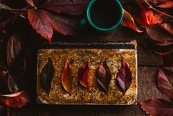 Autumn leaves on old book with cup on wooden surface
