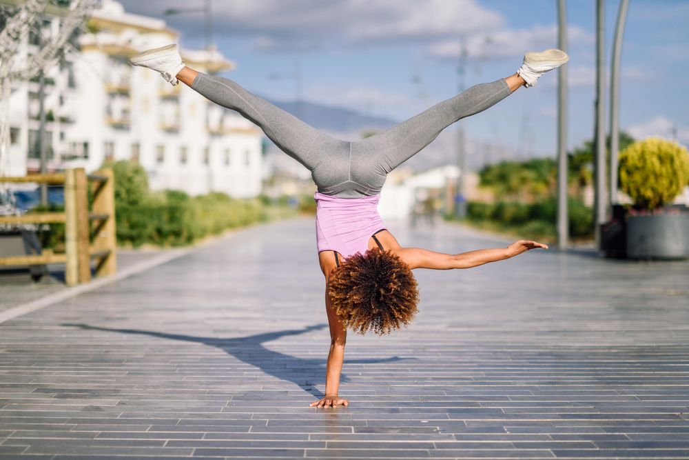 Back of woman in one handed handstand