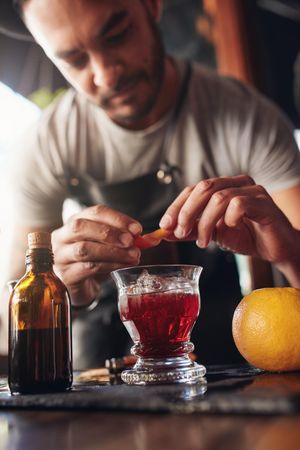 Front view of bartender hands garnishing Negroni cocktail