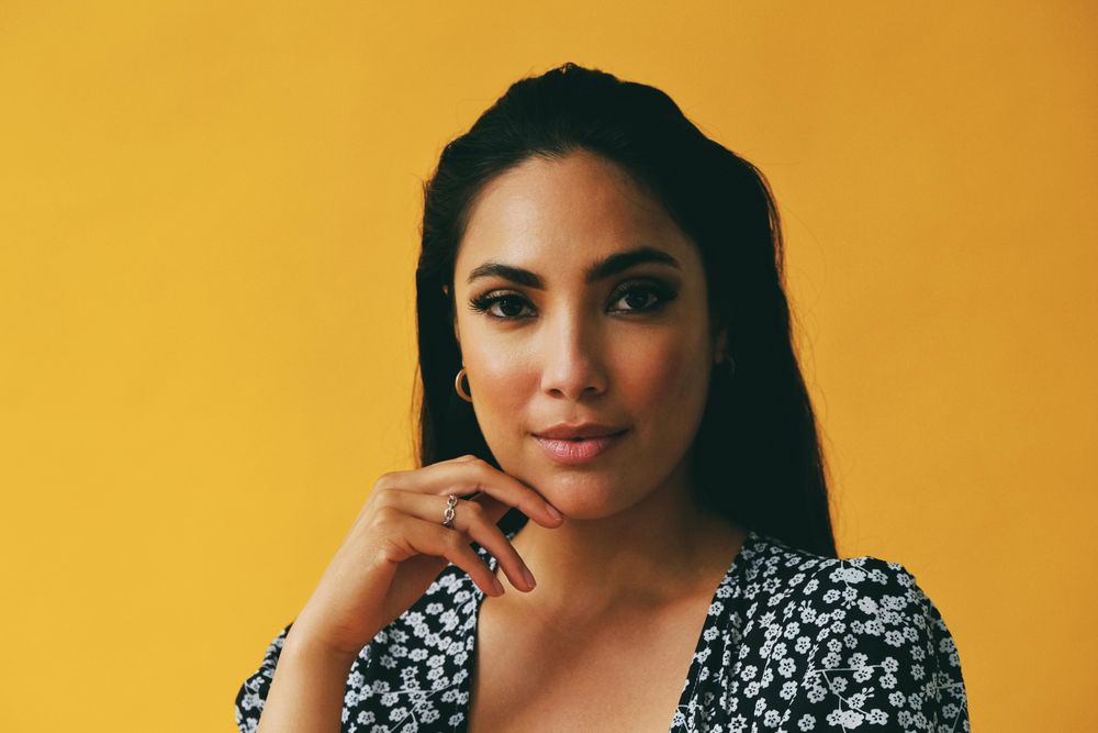Headshot of serious Hispanic woman looking at camera in yellow room, copy space