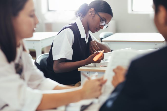 High school students wearing uniform sitting at desk in classroom