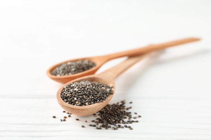 Chia seeds and wooden spoons on wooden background, copy space