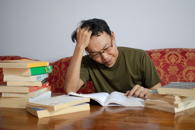Asian young male reading book with frustrated gesture