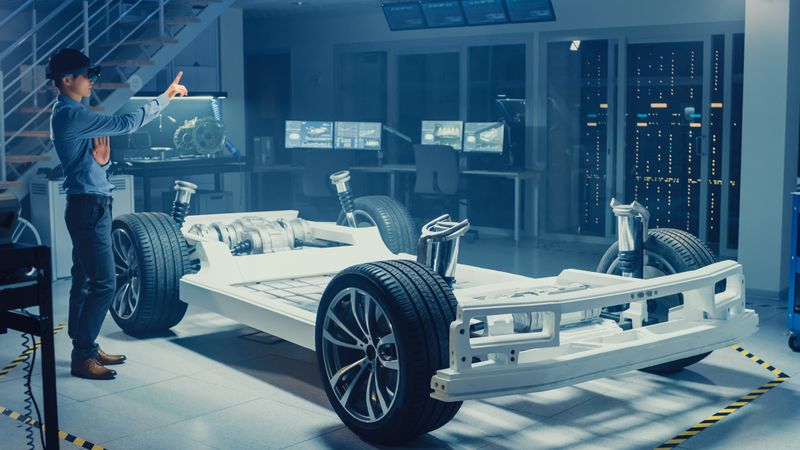 Automotive Engineer Working on Electric Car Chassis Platform, Using Augmented Reality Headset and Making Gestures.