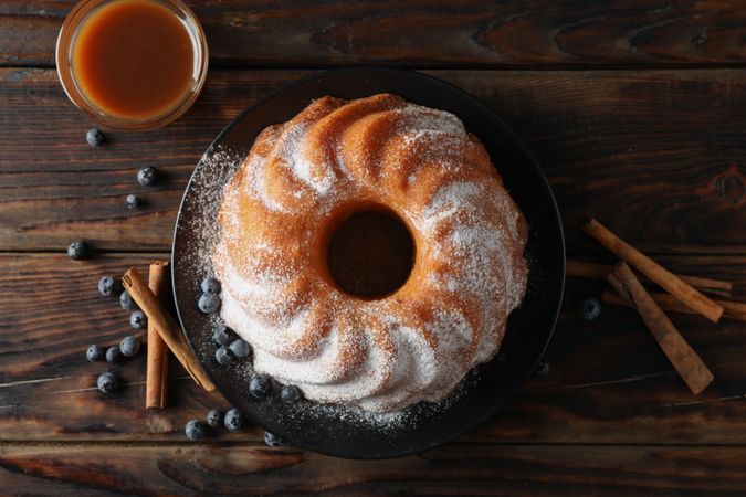 Cake with powder sugar and blueberry on wooden background, top view