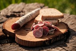 Sliced fuet and bread on wooden plate outdoors
