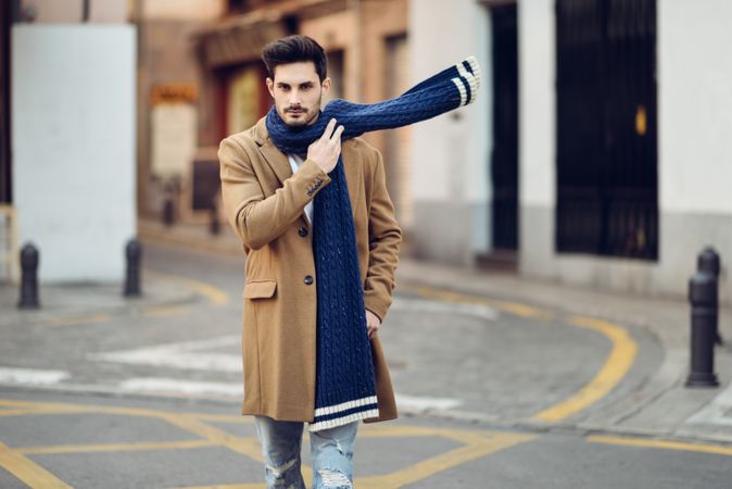 Man strolling in winter jacket adjusting scarf in the street