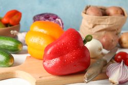 Vegetables, board and knife on wooden background, close up
