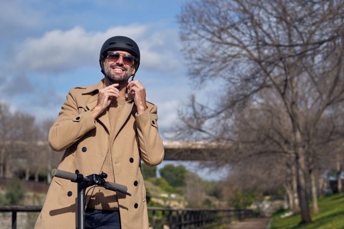 Man putting on helmet on scooter