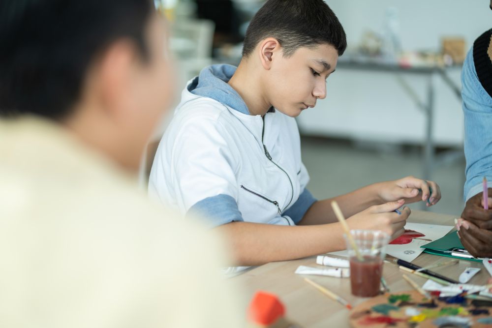 Boy drawing and painting in arts class