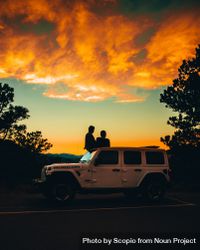 Silhouette of people standing behind a car during sunset 0vmk7b