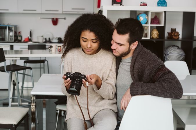 Multiracial couple looking at photo camera at home