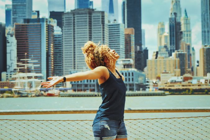 Black woman with her arms outstretched with Hudson River in the background, copy space