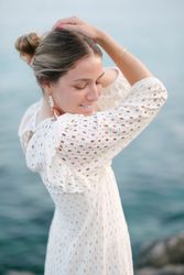 Smiling young romantic woman touching head and looking down near